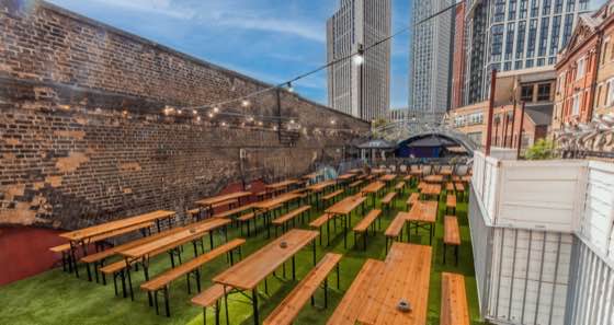 Open-air rooftop terrace with long benches against a brick wall